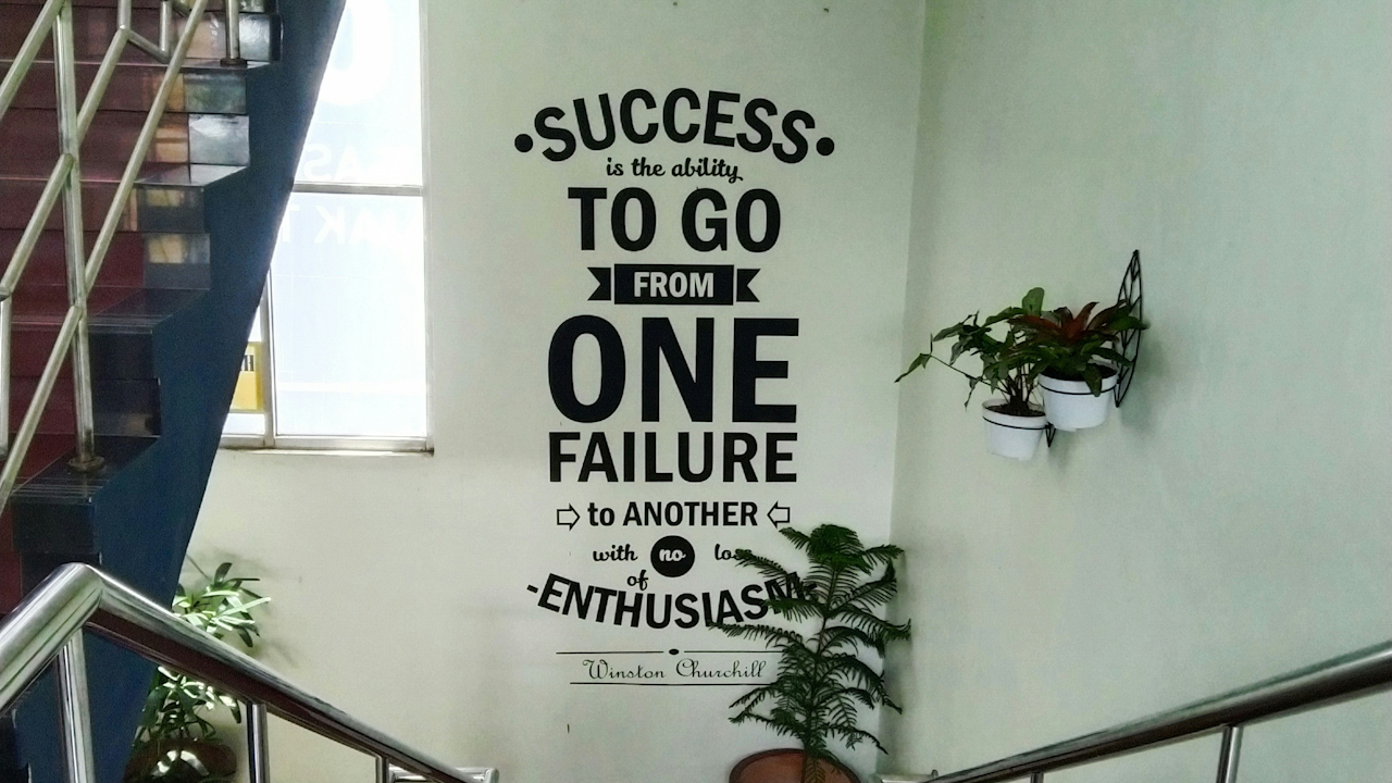 A wall displaying a quote that reads, "SUCCESS is the ability to go from one failure to another with no enthusiasm."