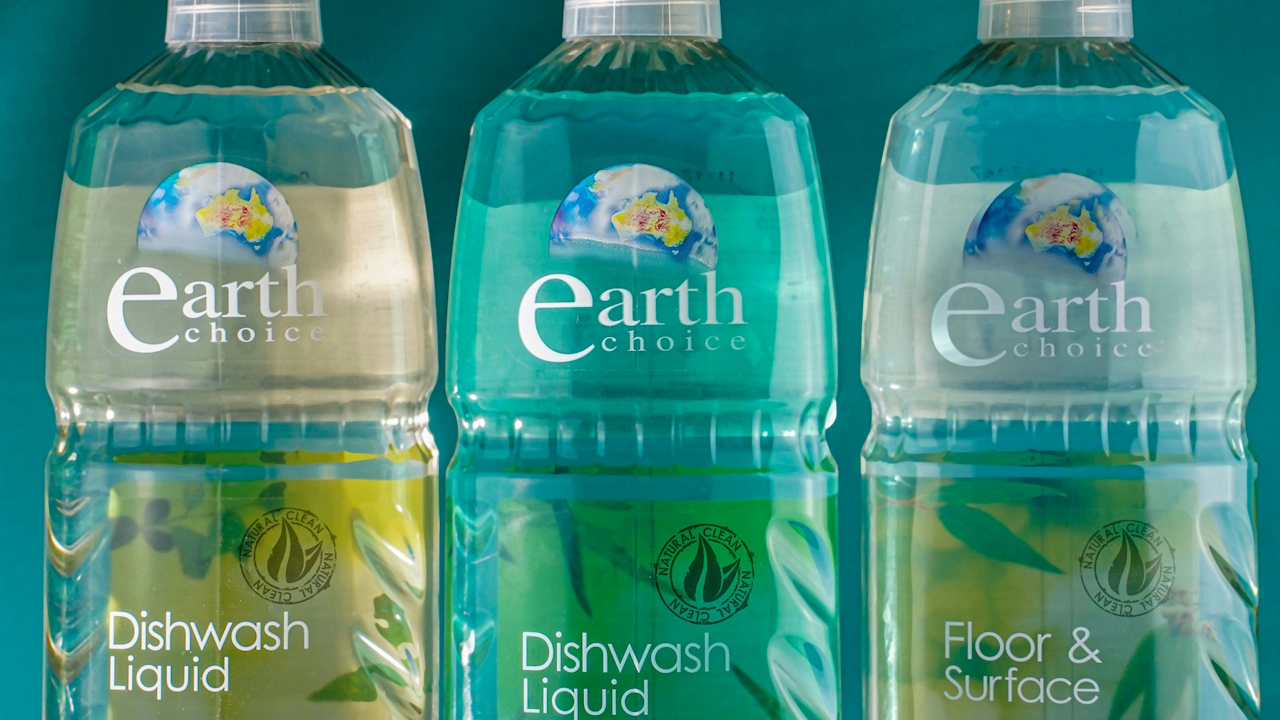 A group of plastic bottles containing various types of cleaning liquids, including dishwash liquid and surface cleaner, arranged together.