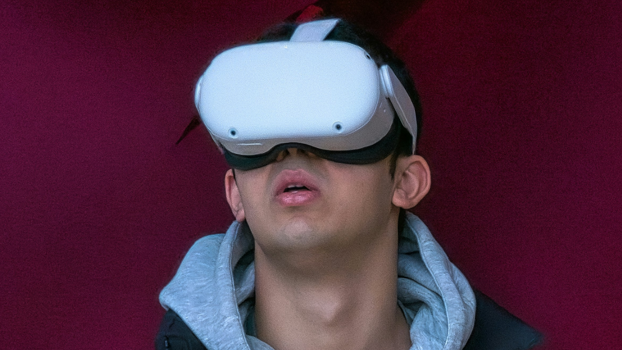 A man wearing virtual reality goggles, with a cool hat, appears to be immersed in a digital experience.
