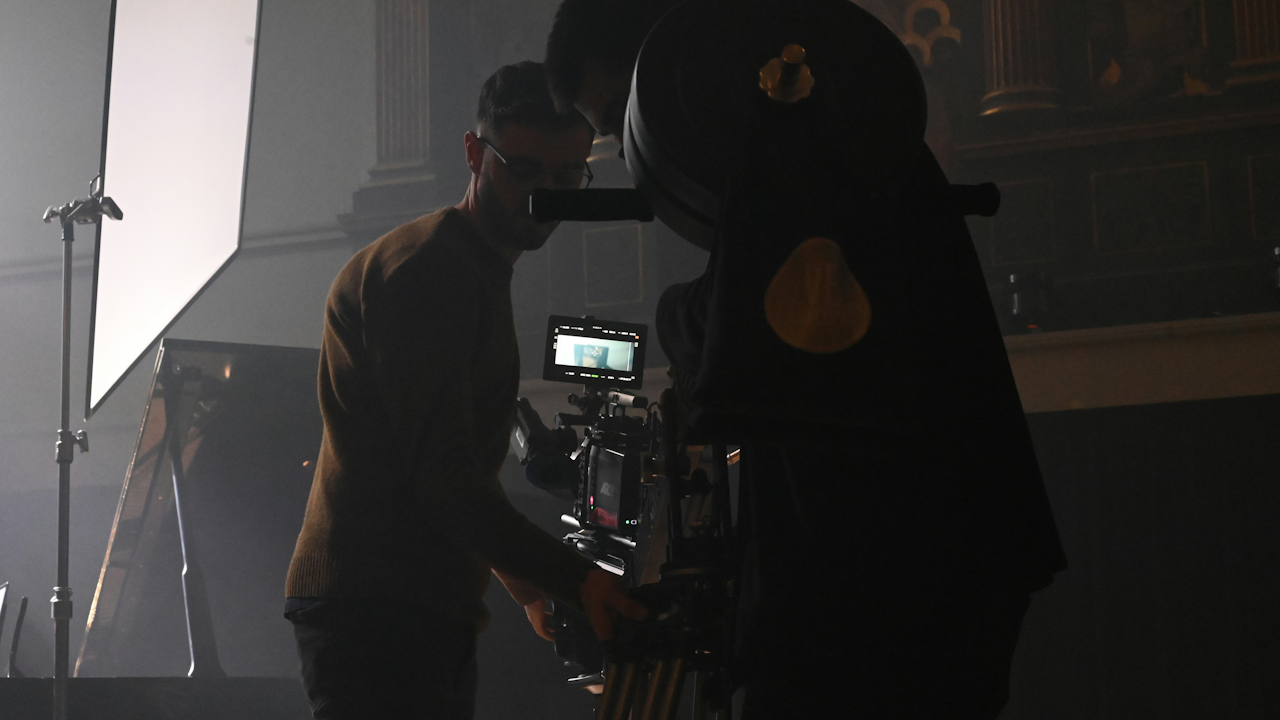 A man stands next to a camera in an indoor setting.