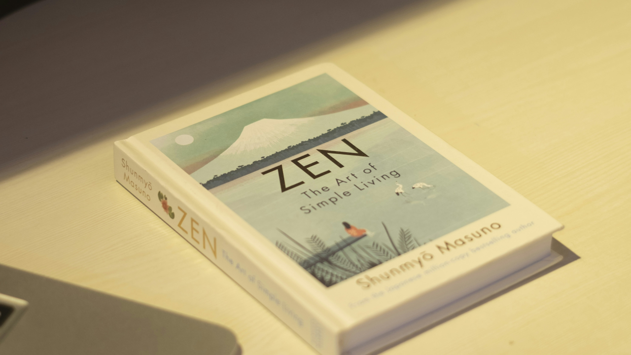 A book titled "ZEN The Art of Simple Living" by Shunmyò Masuno lying on a table with a simple indoor setup.