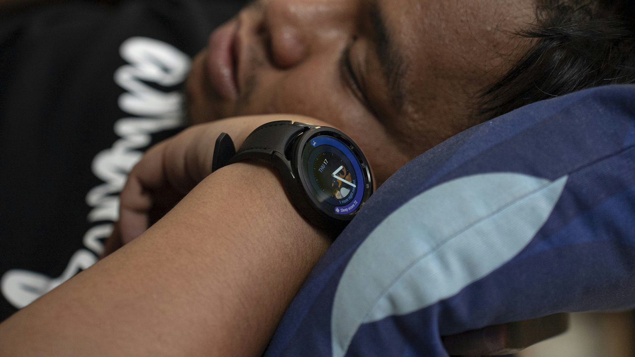 A man sleeping with a watch on his wrist with his finger resting nearby.