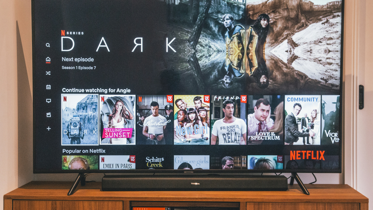 TV screen displaying Netflix series "Dark" with "Next episode" and "Continue watching" options, alongside popular shows like "Friends" and "Emily in Paris."
