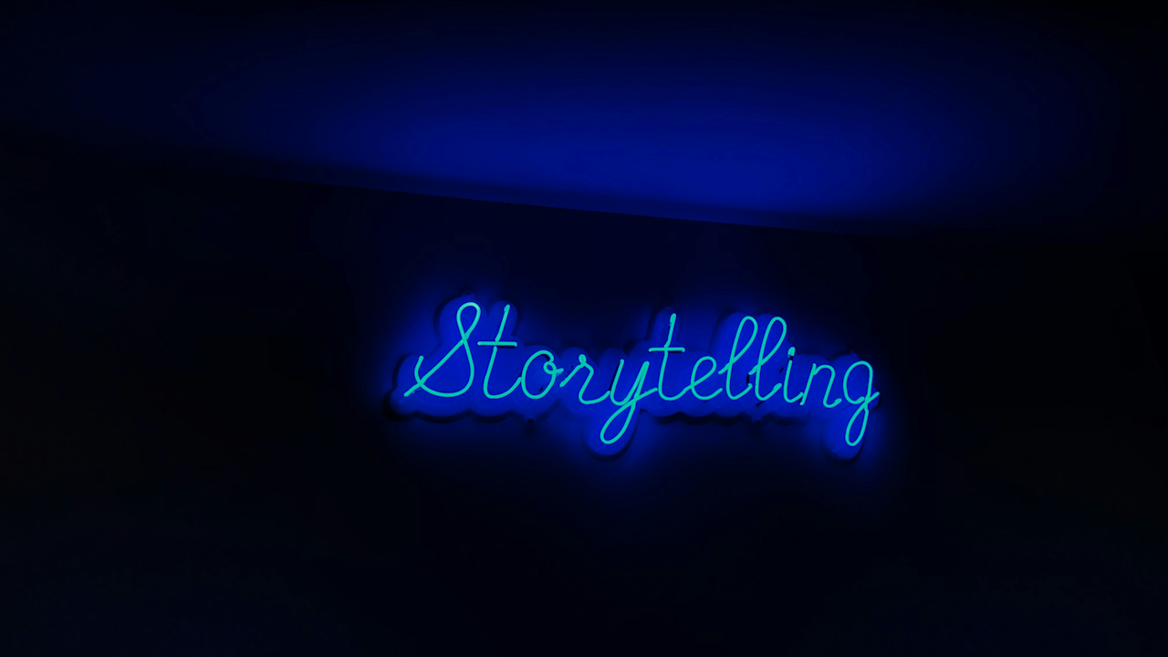 A close-up of a blue neon sign that says "Storytelling" against a dark background.