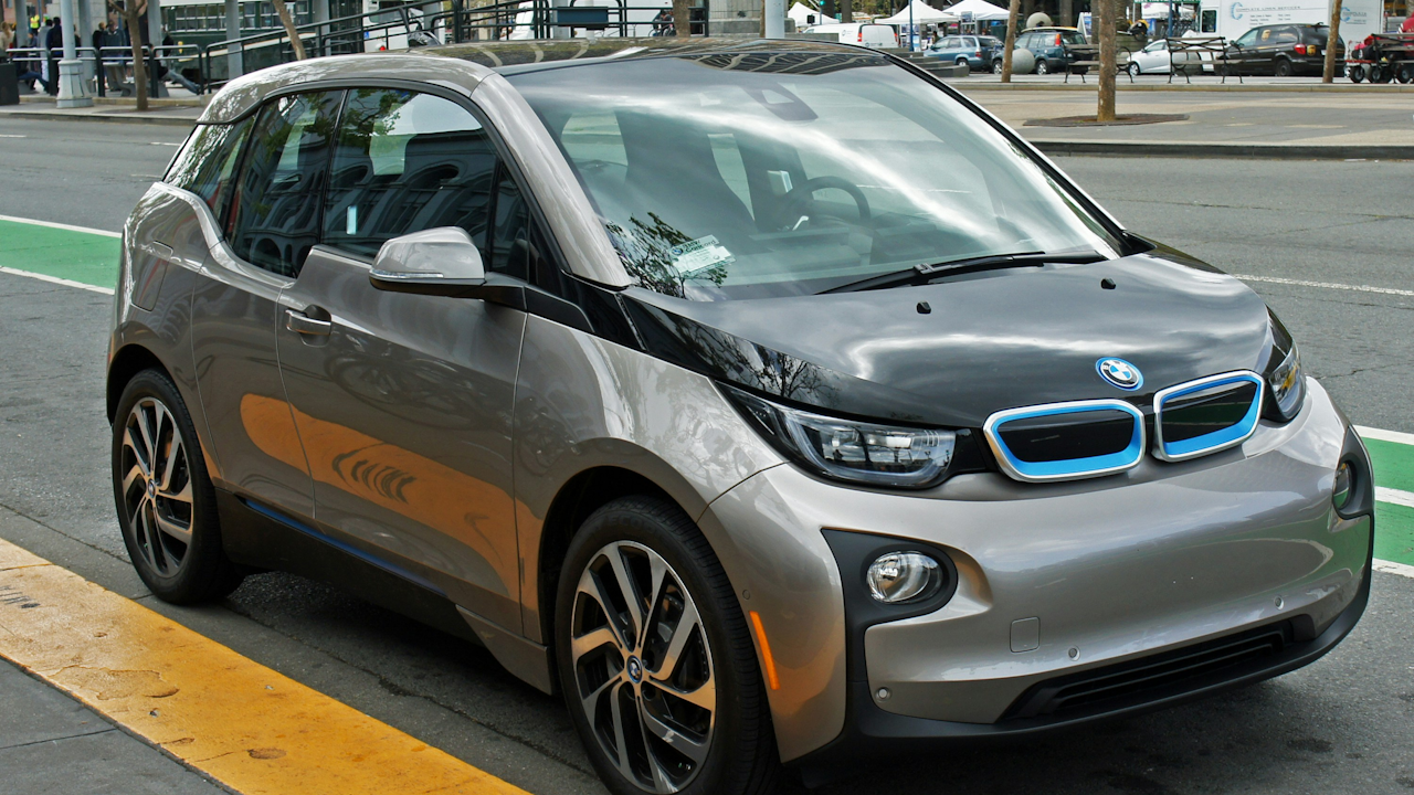A silver car parked on the side of a road, showcasing its alloy wheels and compact hatchback design.